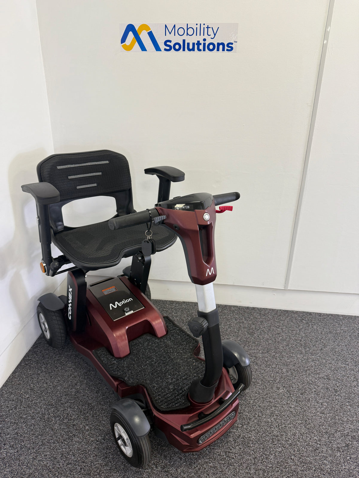 Mobility scooter with 'Mobility Solutions' logo on a gray floor.