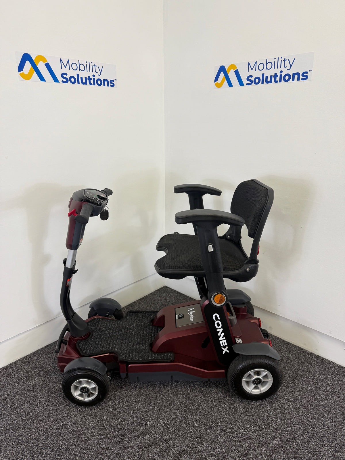 Mobility scooter with 'Mobility Solutions' branding on a white wall.