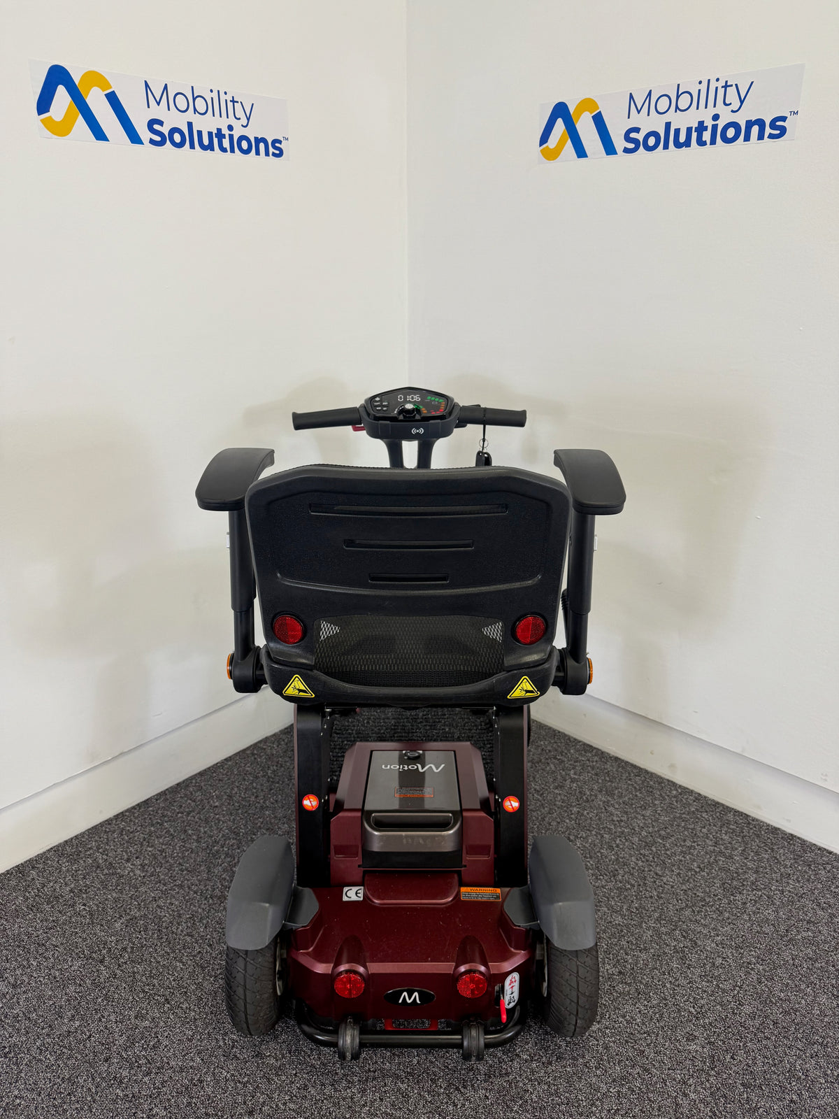 Mobility scooter with 'Mobility Solutions' branding on a white wall.