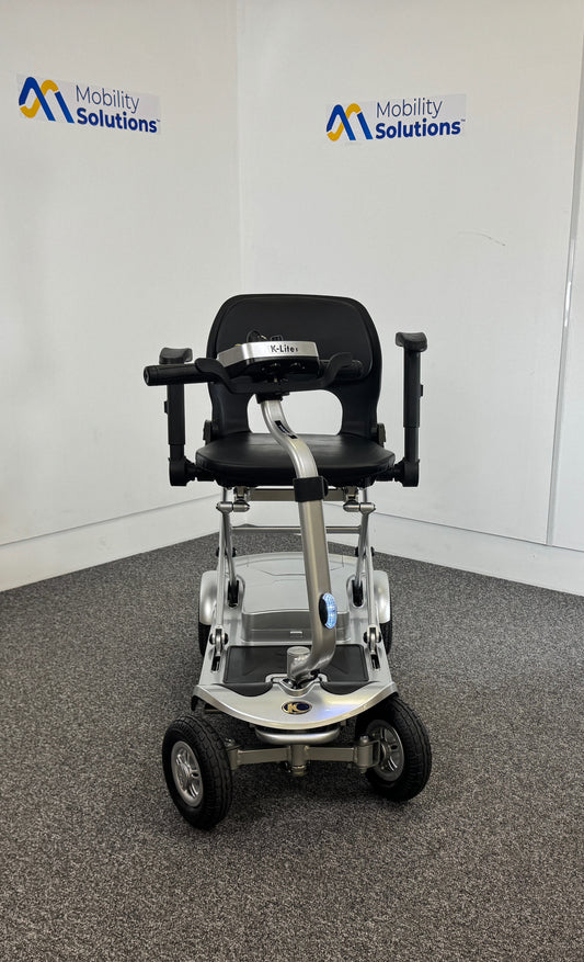 Mobility scooter with a seat in a room with 'Mobility Solutions' branding.