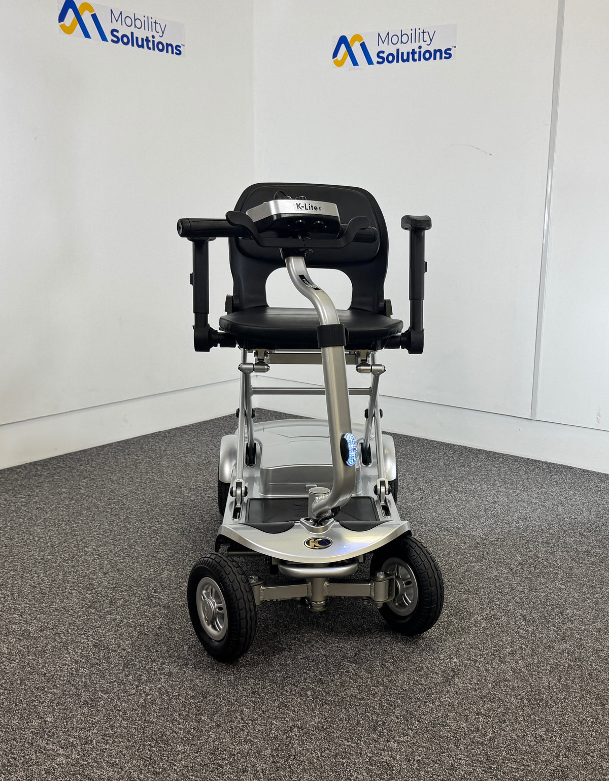 Mobility scooter with adjustable seat on a gray floor, branded 'Mobility Solutions'.